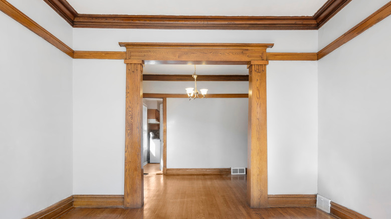 Doorway of empty room in home featuring outdated traditional wooden trim