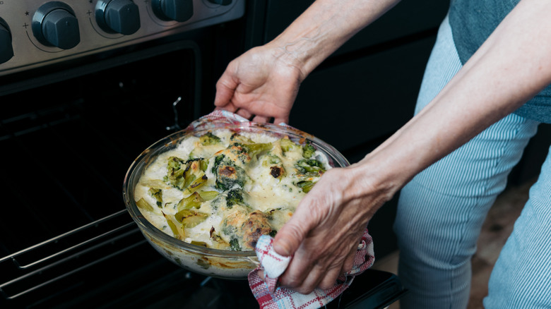 woman taking hot glassware dish out of oven
