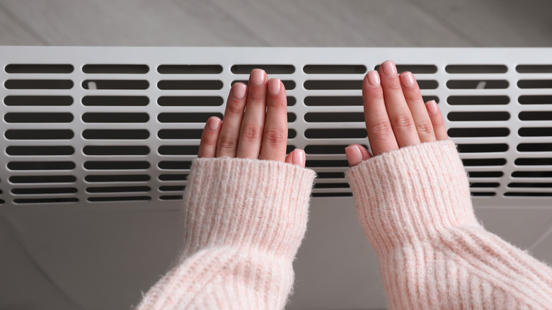 A person warming hands over an electric heater