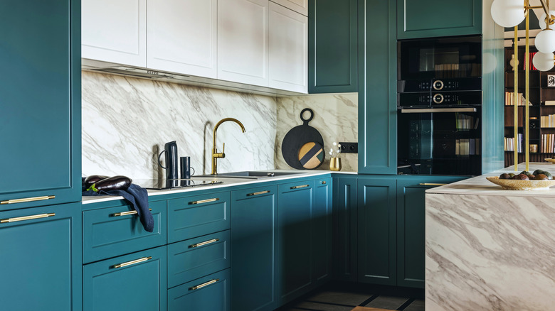A luxurious kitchen with turquoise-colored cabinets and a marble island
