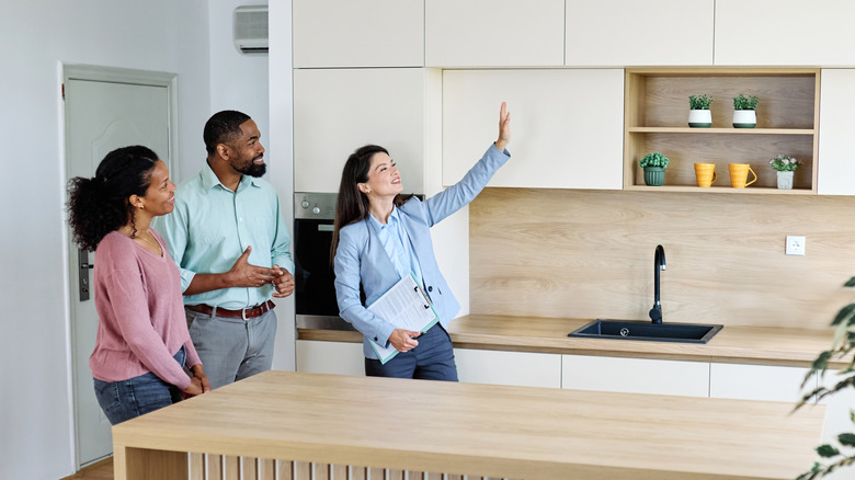 A female real estate agent showing the kitchen of a house to an interested couple