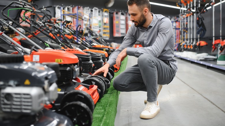 A man examines lawn mowers in a store