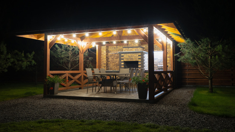 A beautiful, illuminated wooden patio is pictured near a house