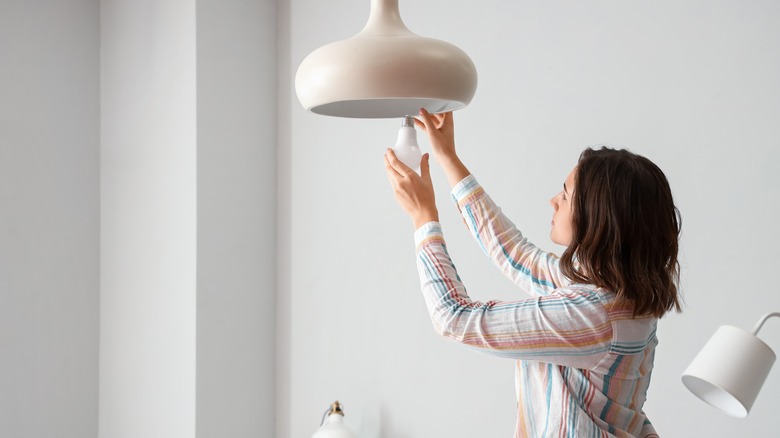 woman changing bedroom lightbulb