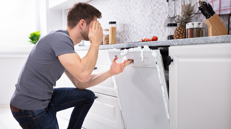 man opening broken dishwasher
