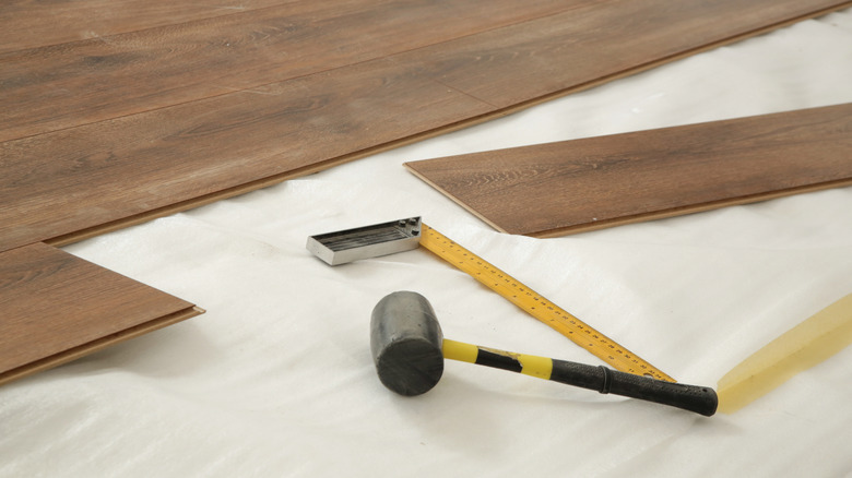 Partially installed vinyl flooring with a rubber mallet and ruler