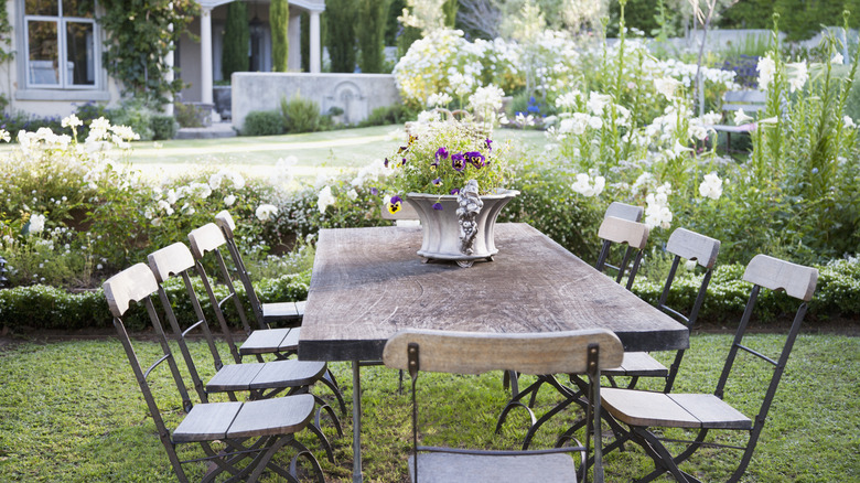 A dining table and chairs outside with flowers in the background