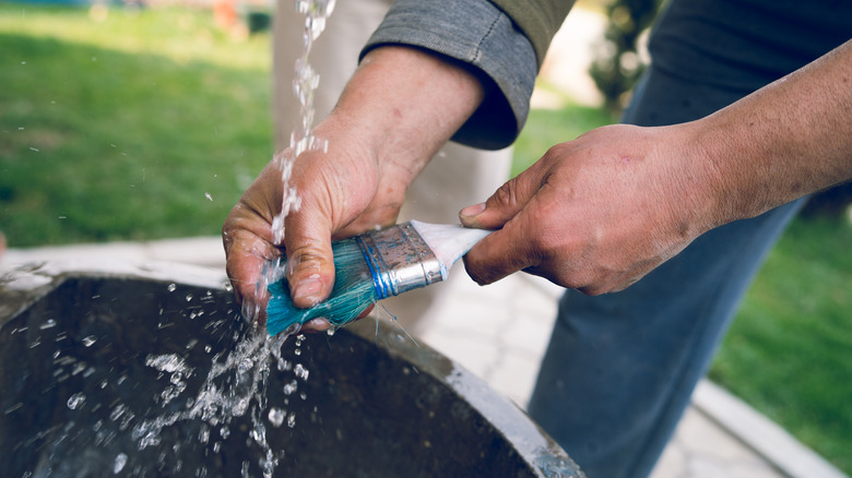 person washing paintbrush 