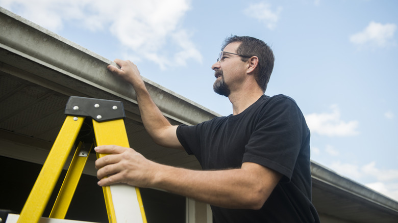 A man inspecting his home's gutters