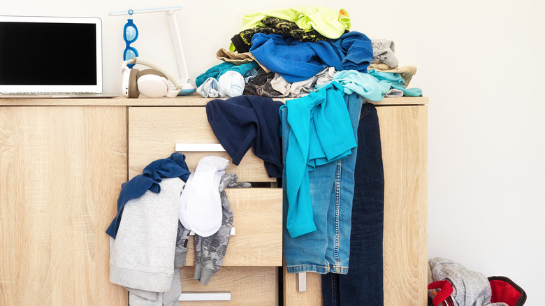 cluttered dresser with clothes