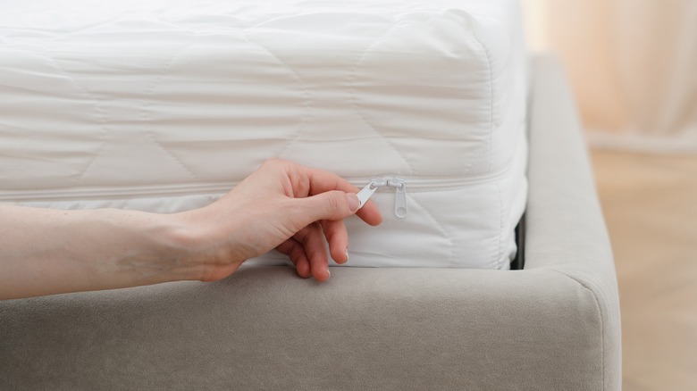 person zipping cover over mattress