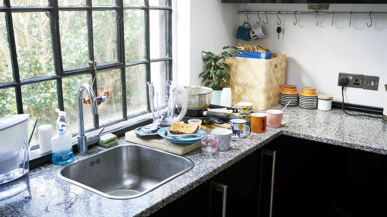 A kitchen counter with dirty dishes and clutter