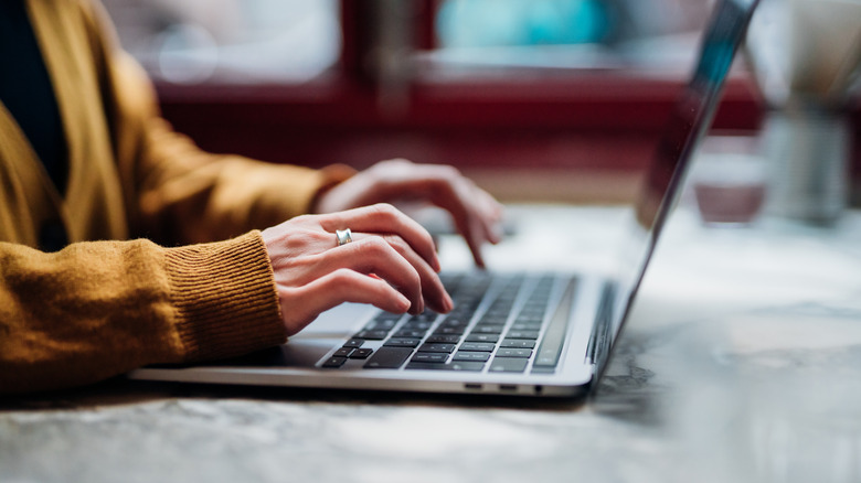 A woman typing on a laptop and filling out a form
