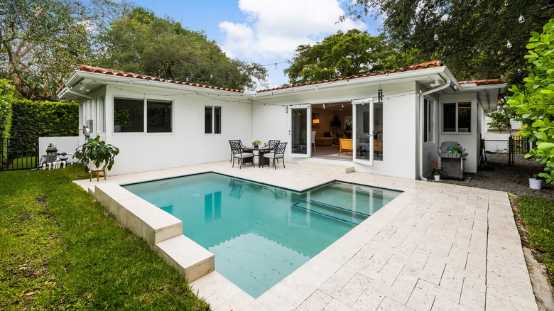 A small inground pool outside a white home