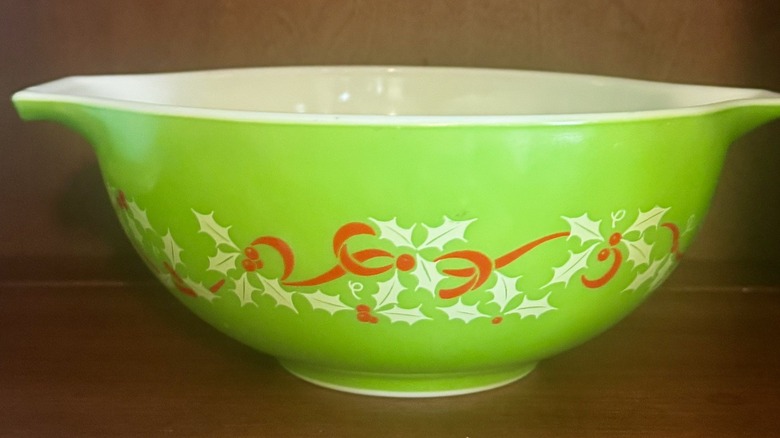 A green Pyrex bowl with a red and white holly design.