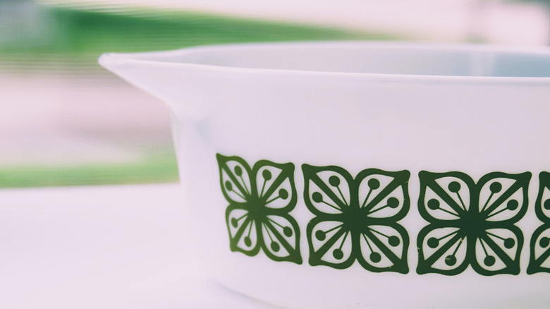 Closeup of a white Pyrex dish with green floral pattern.