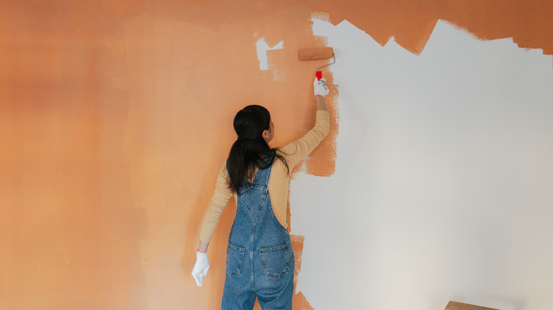 Photo of a woman painting walls of her living room.