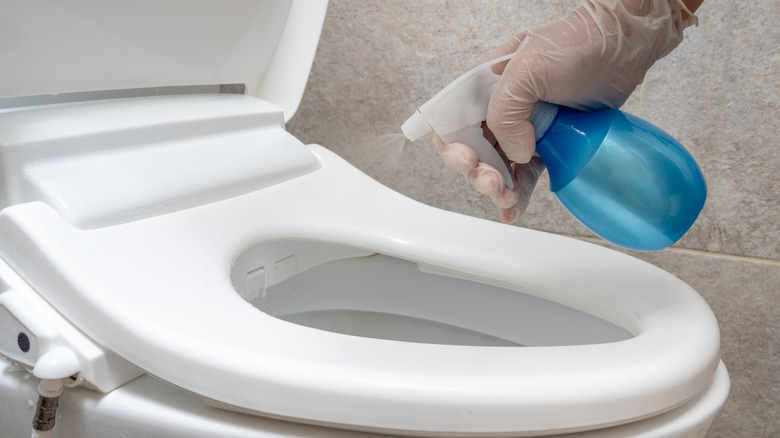Spraying toilet with disinfecting spray