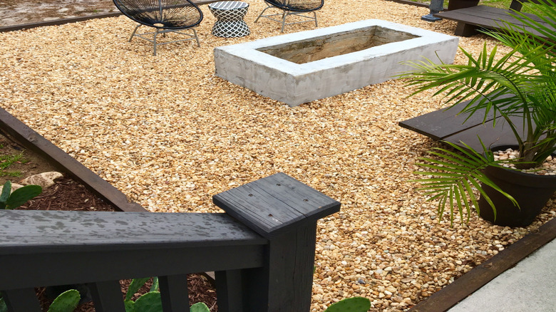 A pea gravel patio sits below chairs, benches, and a fire pit.
