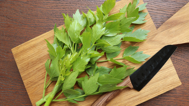 Lovage bunch on wooden chopping board next to a knife