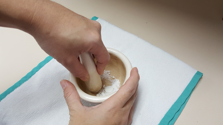 person crushing medicine tablets