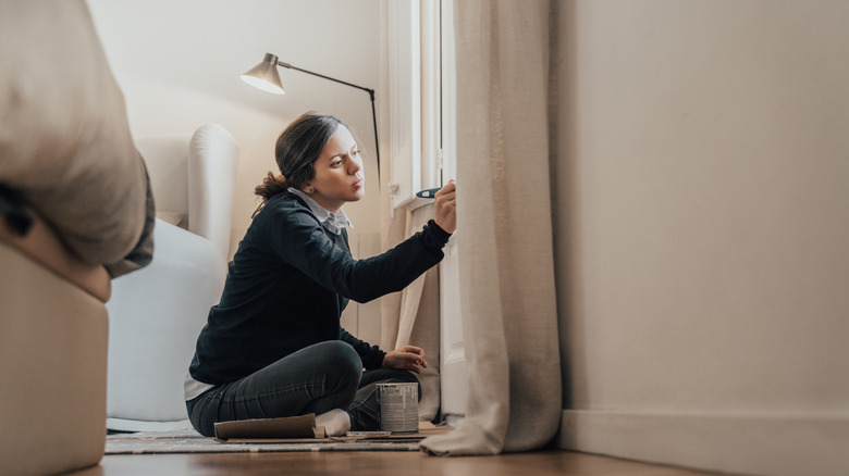 woman painting trim on windows