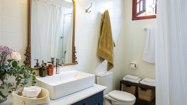 Cozy bathroom with gold finish mirror, farmhouse sink, and flowers