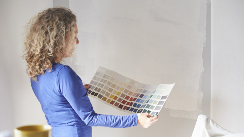 Woman looking at color swatches in blank white room
