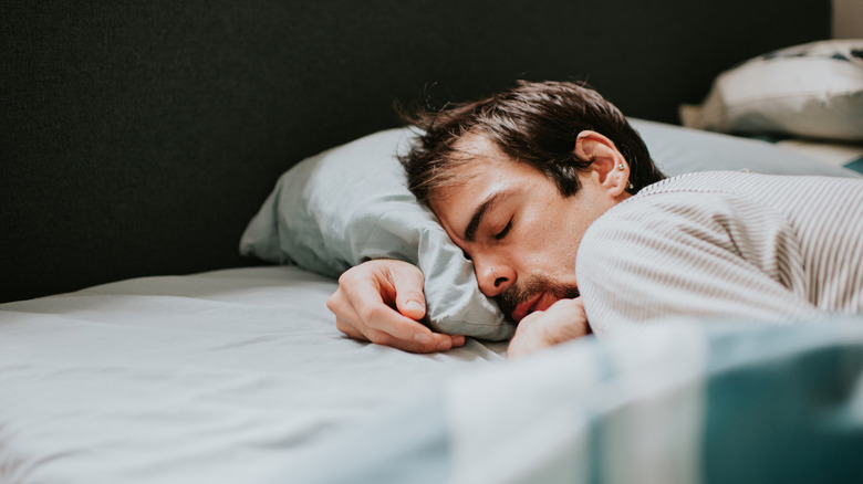 Person sleeping in a bed with arm under the pillow