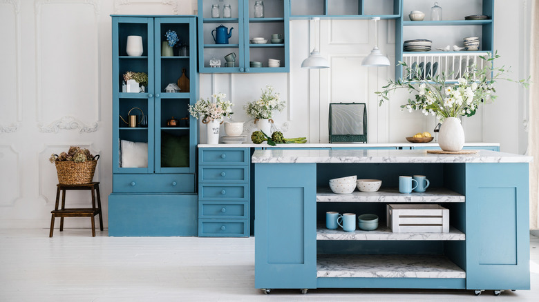 A blue and white kitchen with a matching island with open shelves