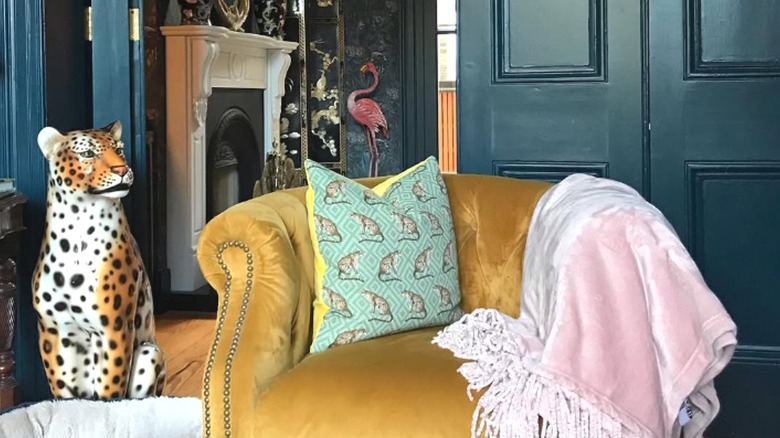 Yellow velvet chair beside leopard statue in moody home