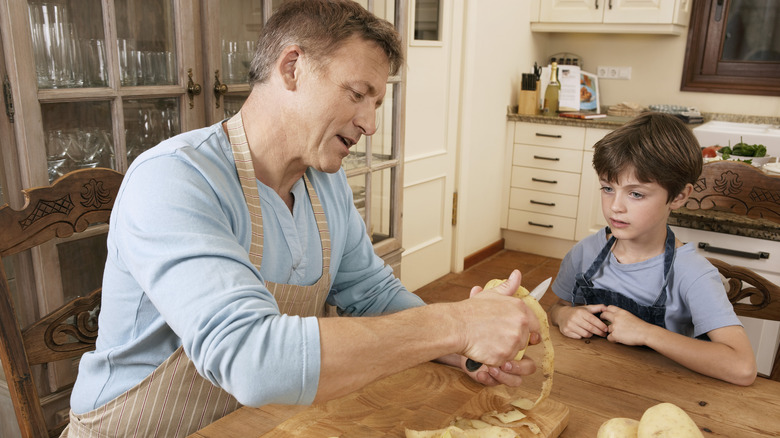 Uomo che mostra al figlio come sbucciare le patate