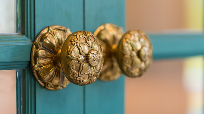 brass doorknobs on green doors