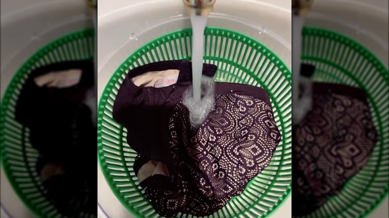 Water runs into a salad spinner filled with clothing,