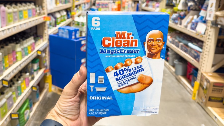 A person holds a box of Mr. Clean Magic Erasers in a store aisle