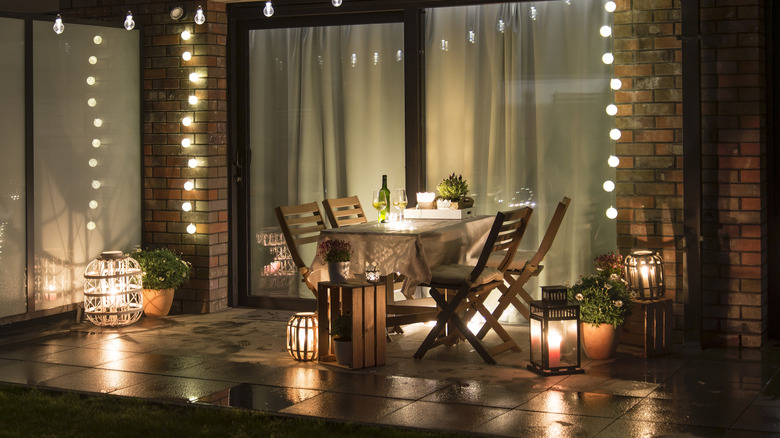 Patio set up for a dinner party with multiple lamps and lights