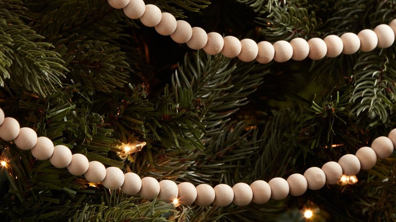 A close-up of a Christmas tree strung with natural wood garland