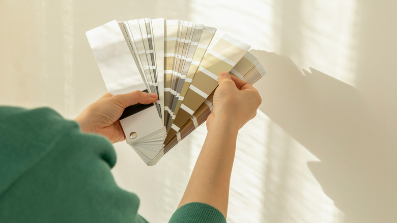 A person choosing paint from a neutral color swatch