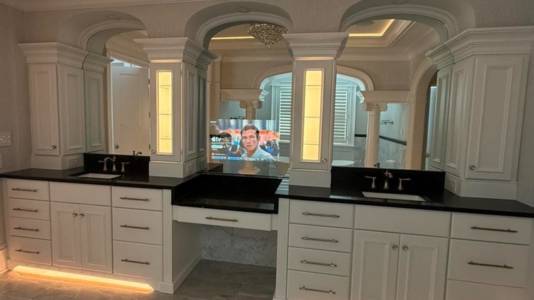 Large double-sink vanity with mirror smart TV in the center.