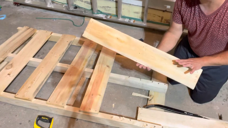 a man demonstrates how to remove boards from a pallet without damaging them
