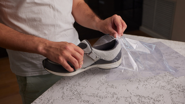 person putting sneakers inside clear plastic bag