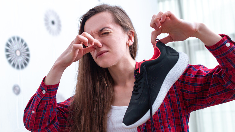 Woman holding smelly shoe