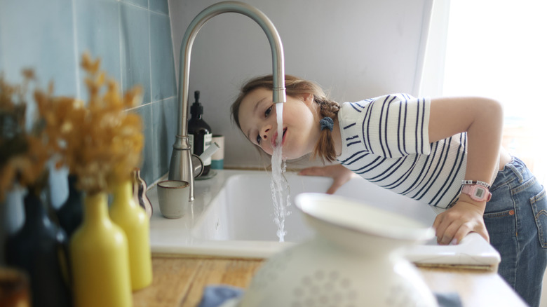 Child drinking directly from kitchen faucet