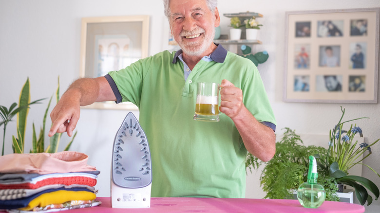 man holding beer and ironing