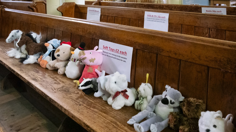 Stuffed animals for sale on a pew at a church rummage sale.