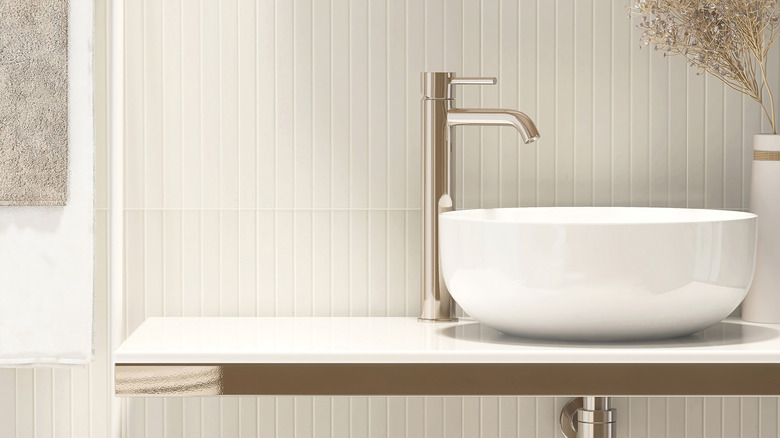 Closeup of bathroom sink with cream panelled backsplash