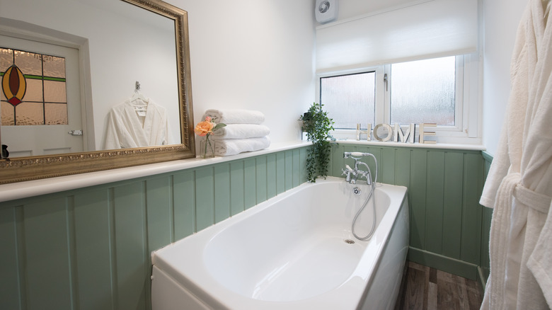 Bathroom with sage panelled walls surrounding bathtub