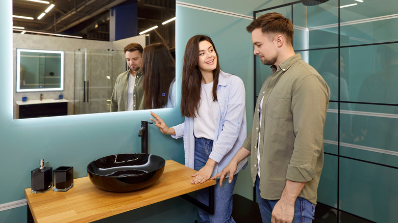 A happy couple pick out bathroom fixtures from a showroom.