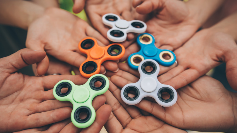 Group of people holding five fidget spinners