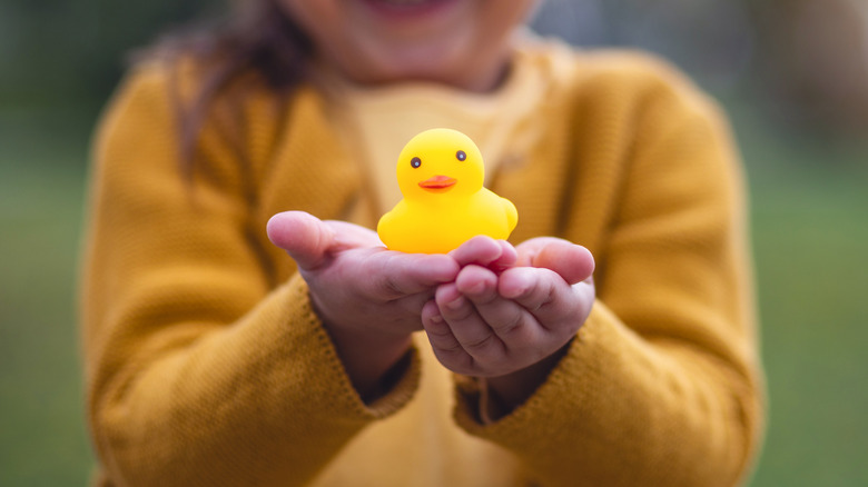 A small person holding a tiny rubber duck